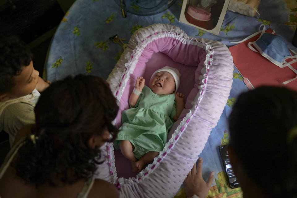 Two-day-old Peyton lies in a basket as her family watches over her in their apartment in the Catia neighborhood of Caracas, Venezuela, Saturday, Sept. 12, 2020. Authorities have not published childbirth related mortality figures for years, but organizations like the Venezuelan Federation of Doctors and the nongovernmental Doctors of Venezuela report the risk for women in labor and newborns is high. (AP Photo/Matias Delacroix)