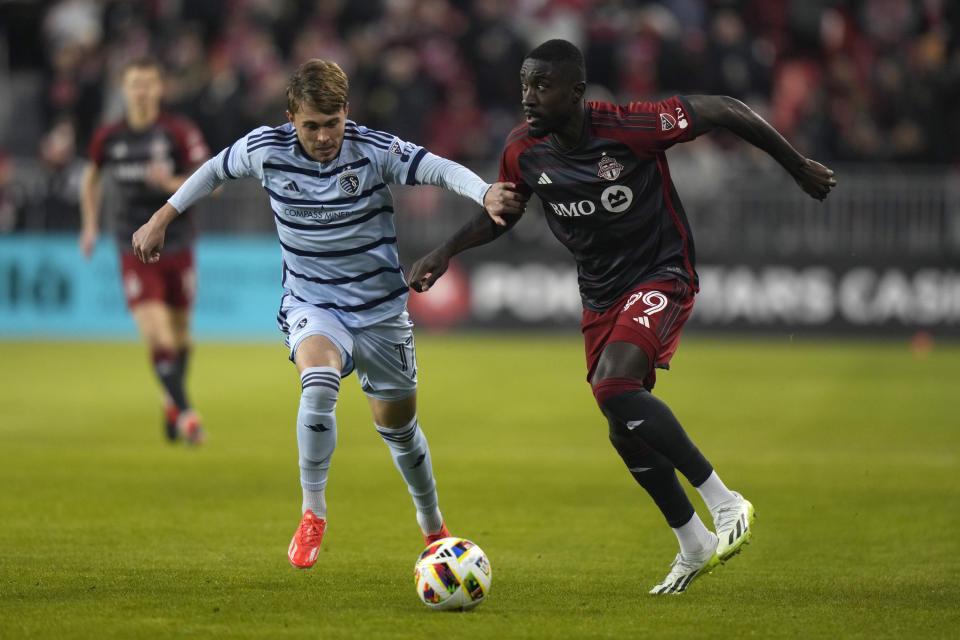 Toronto FC forward Prince Osei Owusu (99) moves the ball upfield as Sporting Kansas City midfielder Jake Davis (17) chases during the first half of an MLS soccer game in Toronto, Ontario, Saturday, March 30, 2024. (Frank Gunn/The Canadian Press via AP)