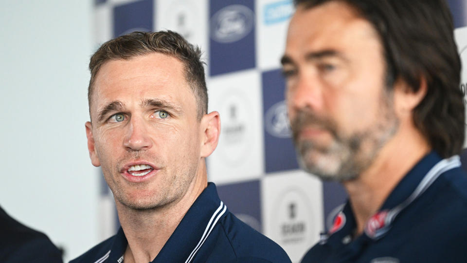 Joel Selwood is pictured at a press conference announcing his retirement, with Geelong coach Chris Scott in the foreground.