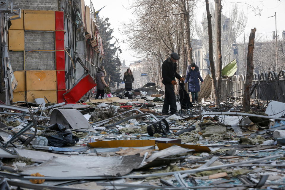 Residents walk along a street near a building destroyed in the course of the Ukraine-Russia conflict