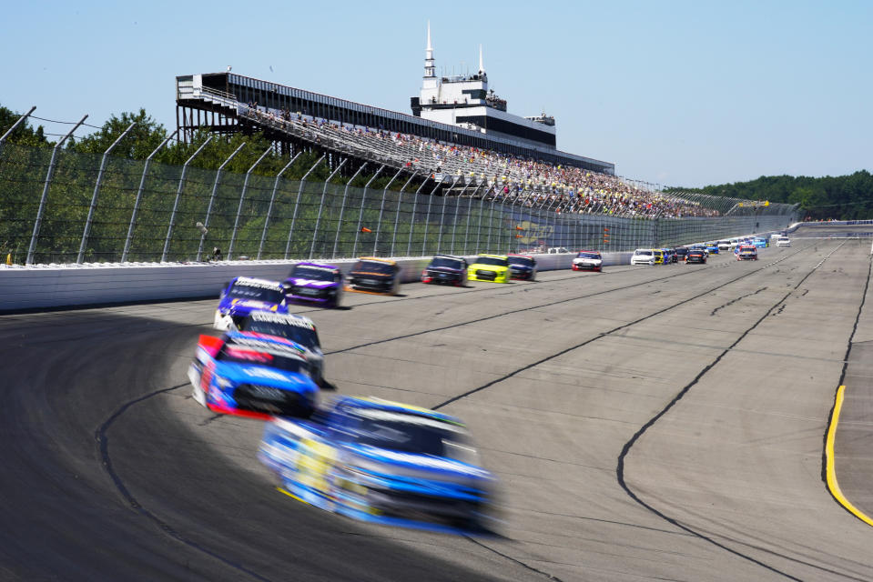 Trucks speed past the grandstand during the NASCAR Truck Series Race at Pocono Raceway, Saturday, July 23, 2022 in Long Pond, Pa. (AP Photo/Matt Slocum)