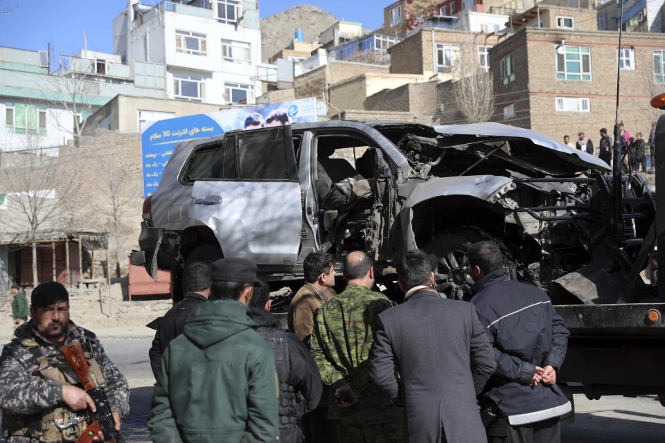 Afghan security officers inspect the site of a bomb attack in Kabul, Afghanistan, Saturday, Jan. 16, 2021. A sticky bomb attached to an armored police Land Cruiser SUV exploded Saturday in the western part of the capital, Kabul, killing few policemen and wounding another, Kabul police spokesman Ferdaws Faramarz said. (AP Photo/Rahmat Gul)