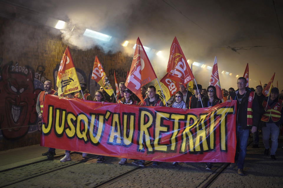 FILE - Railway workers hold a banner reading 'Until withdrawal' during a demonstration in Lyon, central France, Wednesday, March 22, 2023. With President Emmanuel Macron thousands of miles away in China, French protesters and unions returning to the streets continue to reveal cracks in his domestic political authority. Hundreds of thousands are expected again for the 11th day of nationwide resistance to raising the retirement age from 62 to 64 Thursday, April 6 as the controversial law is being considered by the Constitutional Council. (AP Photo/Laurent Cipriani, File)