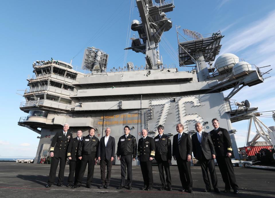 Japanese Prime Minister Fumio Kishida, fifth from left, U.S. Ambassador to Japan Rahm Emanuel, fourth from left, and Japanese Defense Minister Yasukazu Hamada pose for a photo with U.S. military officials on the USS Ronald Reagan, in Sagami Bay, southwest of Tokyo, Sunday, Nov. 6, 2022. Kishida, at an international fleet review Sunday, said his country urgently needs to build up military capabilities as it faces worsening security environment in the East and South China Seas and threats from North Korea’s nuclear and missile advancement and Russia’s war on Ukraine.(Kyodo News via AP)