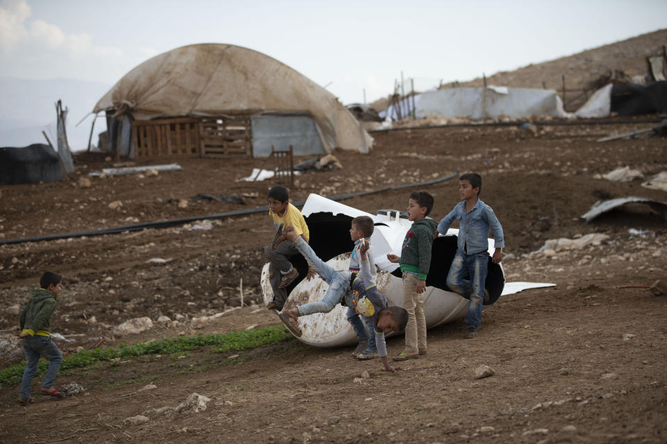Palestinian children play by a destroyed tank in Khirbet Humsu in Jordan Valley in the West Bank, Friday, Nov. 6, 2020. Israeli troops with bulldozers and heavy equipment demolished 18 tents and other structures that housed 74 people, including 41 minors, according to the Israeli rights group B'Tselem. COGAT, the Israeli military body in charge of civilian affairs in the West Bank, said an "enforcement activity" was carried out against seven tents and eight pens that were "illegally constructed" in a firing range. (AP Photo/Majdi Mohammed)
