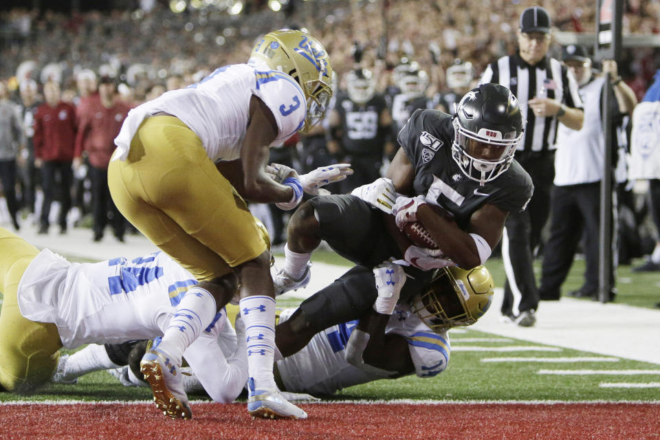 Washington State wide receiver Travell Harris, right, scores a touchdown as he is brought down by UCLA linebacker Krys Barnes, second from right, and defensive back Jay Shaw, left, in front of Rayshad Williams during the first half of an NCAA college football game in Pullman, Wash., Saturday, Sept. 21, 2019. (AP Photo/Young Kwak)