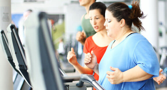 An overweight woman working out with a trainer in the gym