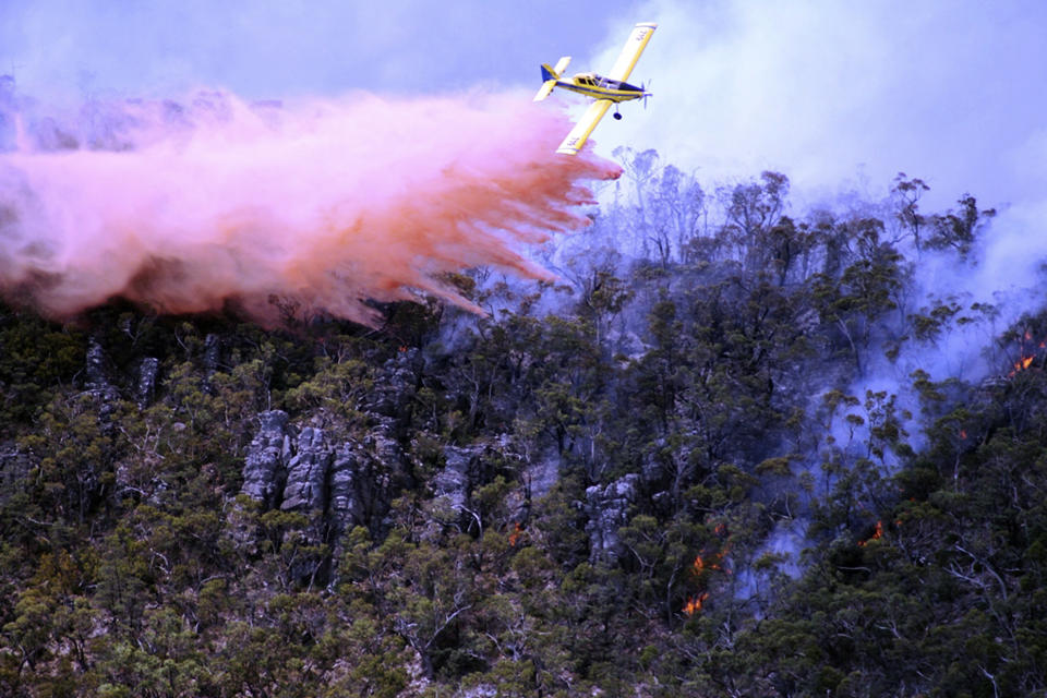 In this Thursday, Jan. 16, 2014 photo released by Victoria Country Fire Authority, a water bomber works over a large fire burning throughout Victoria's Grampians region. Fire authorities in Victoria said there are 68 fires burning at present with stronger winds expected Friday afternoon, urging residents in these affected regions to evacuate. (AP Photo/Country Fire Authority)