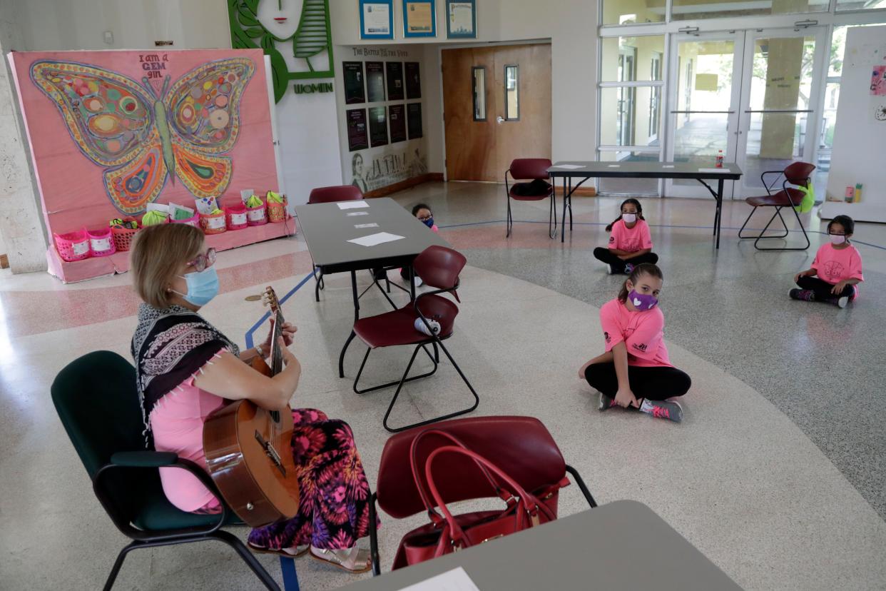 Maria Elena Vallejo, left, plays guitar and sings at the Girl's Empowerment and Mentoring (G.E.M.) Summer Arts Camp during the coronavirus pandemic on Wednesday, July 15, 2020, in Miami, Fla. This Miami-Dade County summer camp program is operating at limited capacity, and has enhanced health screenings and sanitizing procedures, practices social distancing and requires wearing of face coverings.