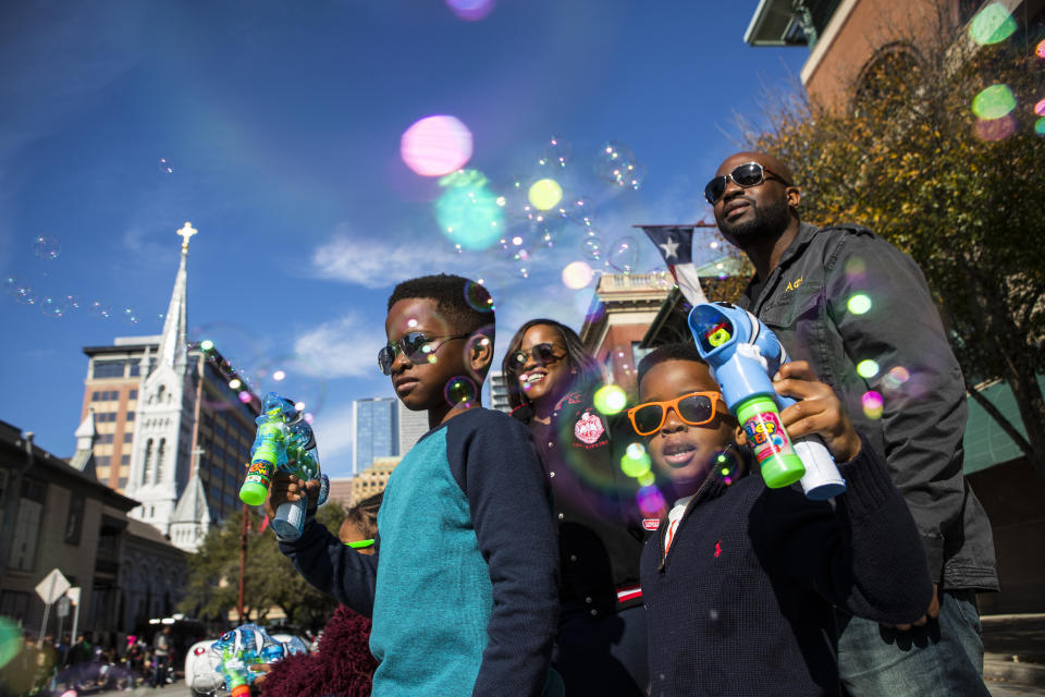 In this Monday, Jan. 15, 2018 photo, Jaylen Chukudebelu, left, and his brother, Cameron, blow bubbles as they watch The "Original" MLK, Jr. Parade with their parents, Khia and Chuk, in front of Minue Maid Park in Houston. For more than two decades, competing MLK Day parades have been held in Houston. This year, the city of Houston threw its official support behind one parade, the 41st annual “Original” MLK, Jr. Parade, hoping the city could unite behind only one parade. But organizers of the other parade, the 25th annual MLK Grande Parade, will still be holding its event and they say they have no plans to stop having their own parade. (Brett Coomer/Houston Chronicle via AP)