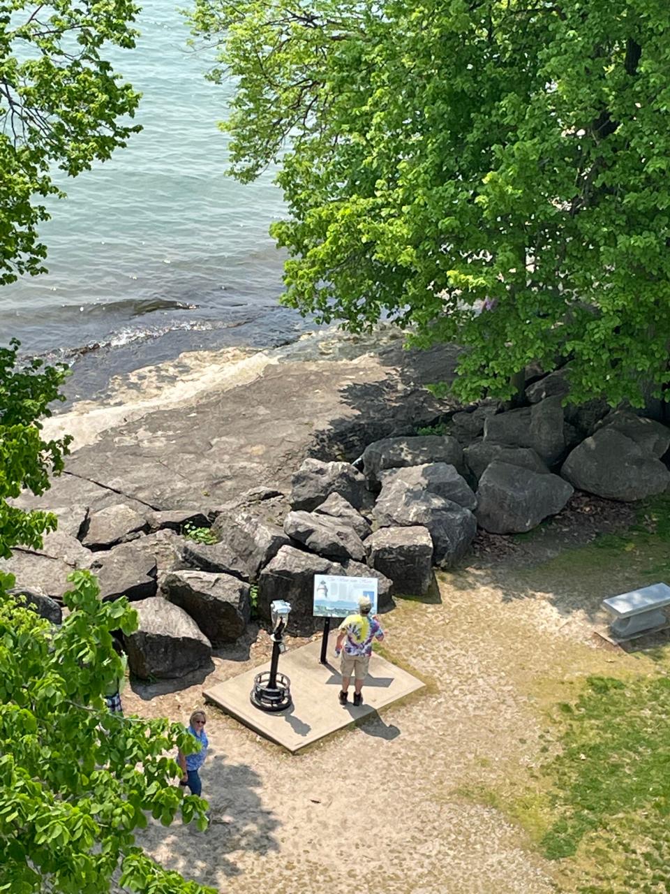 A visitor enjoys the view of Lake Erie from the shore at the base of the lighthouse.