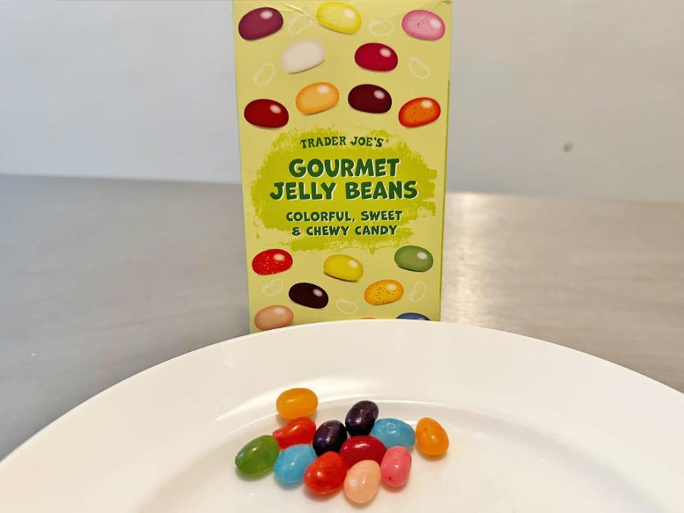 Green box of Trader Joe's gourmet jelly beans with a plate of multicolored jelly beans in front