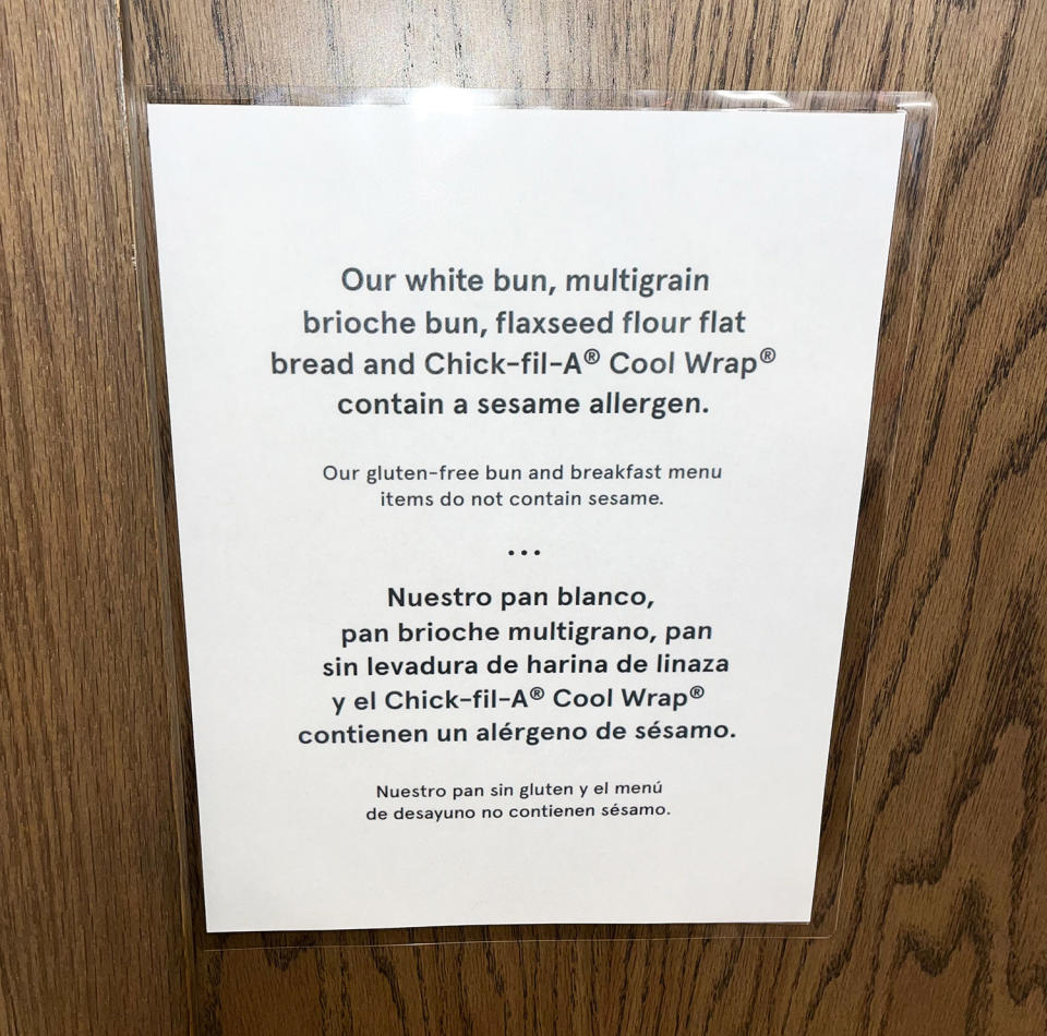 A sign on a door reads "Our white bun, multigrain brioche bun, flaxseed flour flat bread and Chick-fil-A cool wrap contain a sesame allergen"