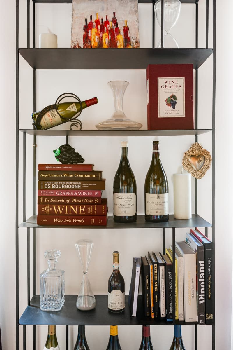 A shelf with cookbooks and wine items.