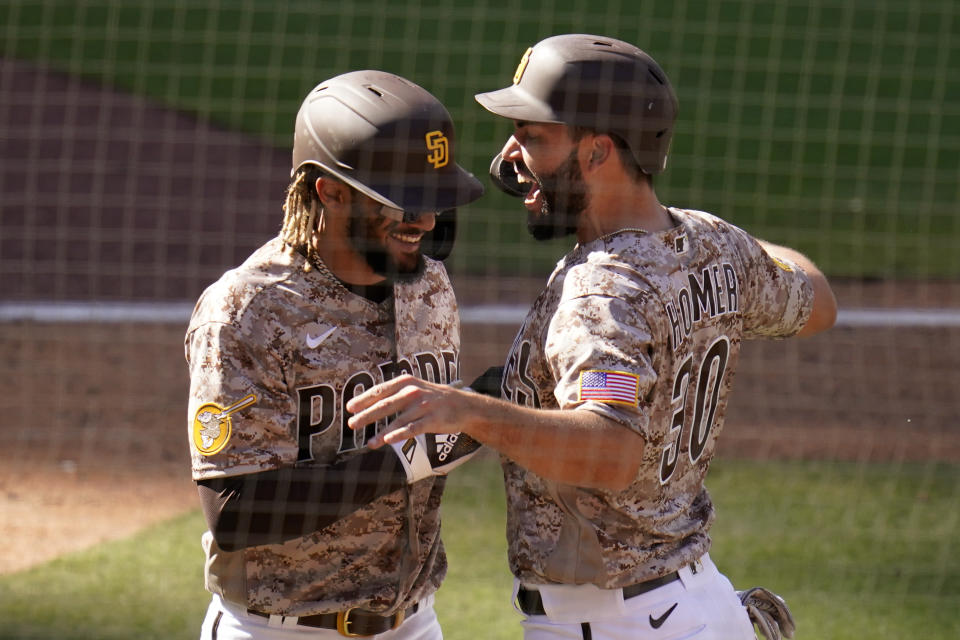 San Diego Padres' Eric Hosmer, right, reacts with teammate Fernando Tatis Jr after both scored off a two-RBI double by Tommy Pham during the eighth inning of a baseball game against the Los Angeles Dodgers, Sunday, April 18, 2021, in San Diego. (AP Photo/Gregory Bull)