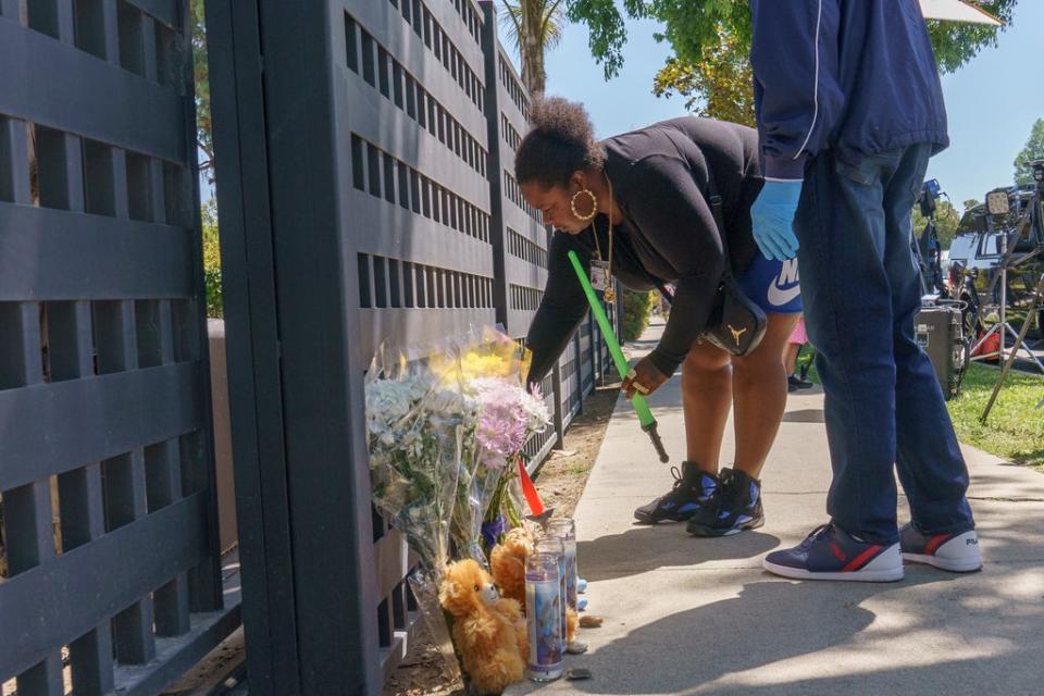 La trabajadora del condado de Los Ángeles, Tiana Baudin, deja varios juguetes en el exterior de una casa tipo rancho en el barrio de West Hills, en el Valle de San Fernando, en Los Ángeles, el lunes 9 de mayo de 2022 (Copyright 2022 The Associated Press. All rights reserved.)