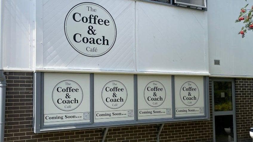 The Coffee & Coach Cafe, brick building on the lower half and white panelling on the upper half of the building with the writing Coffee & Coach Cafe.