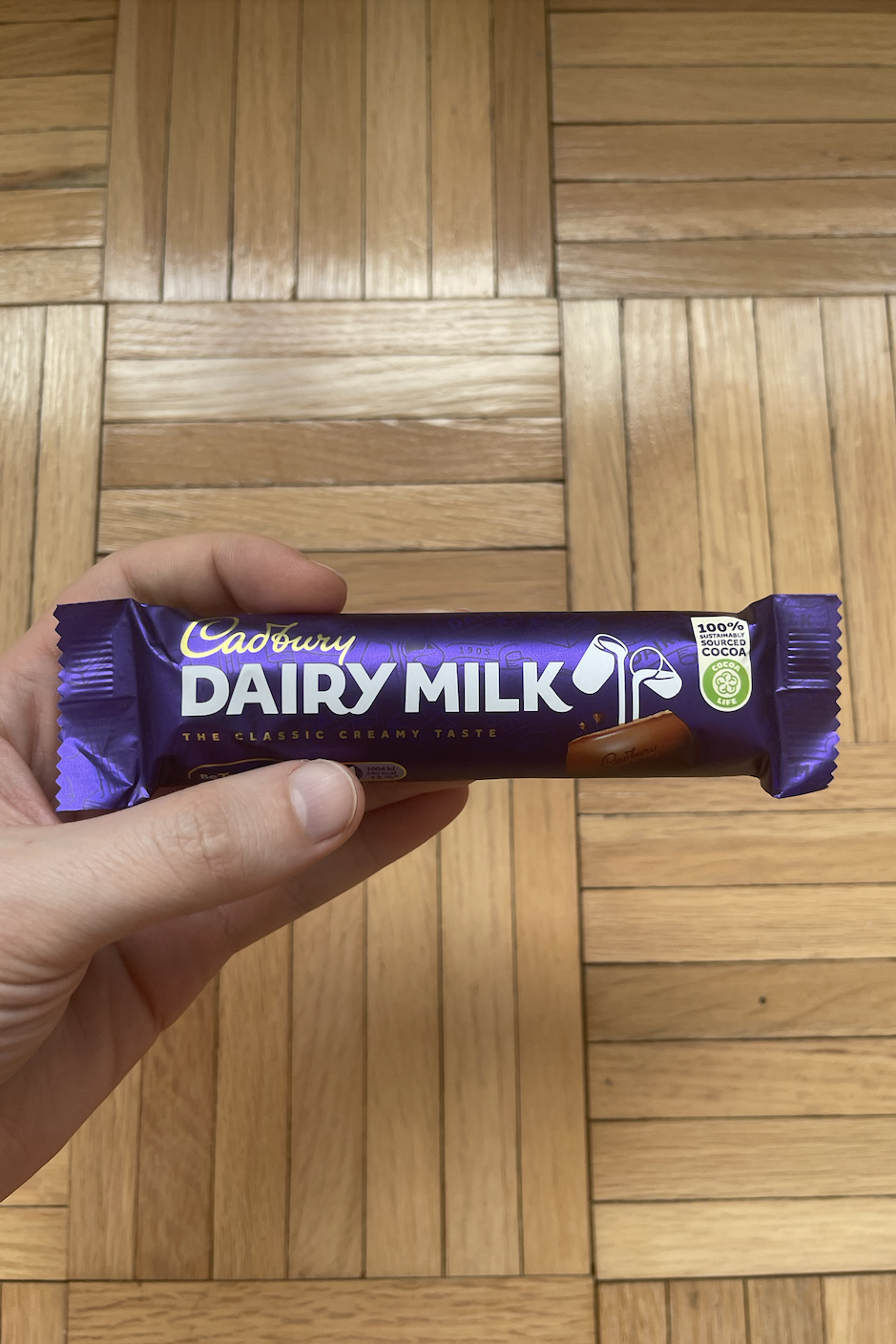 Hand holding a Dairy Milk bar