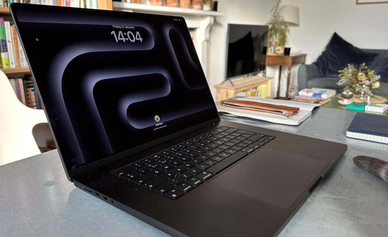  A Space Black Apple MacBook Pro 16-inch M3 sitting on a grey/blue table. 