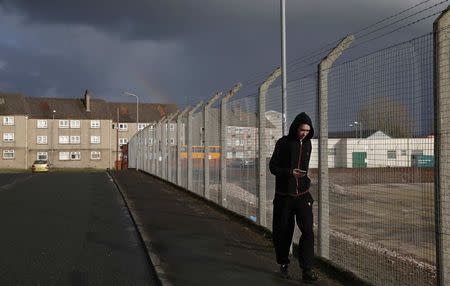 A pedestrian walks past the former site of the Johnnie Walker whisky plant in Kilmarnock, Scotland March 25, 2014. REUTERS/Suzanne Plunkett