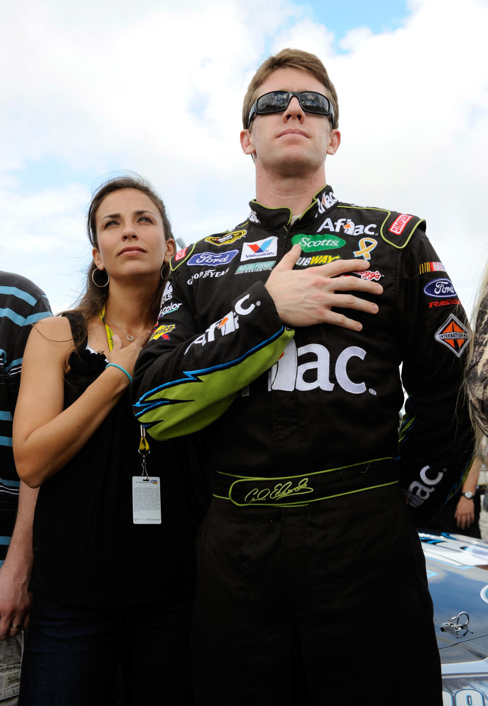 HOMESTEAD, FL - NOVEMBER 20: Carl Edwards, driver of the #99 Aflac Ford, and wife Kate Edwards cover their heart during the singing of the national anthem as they stand next to his car on the grid before the NASCAR Sprint Cup Series Ford 400 at Homestead-Miami Speedway on November 20, 2011 in Homestead, Florida. (Photo by Jared C. Tilton/Getty Images)