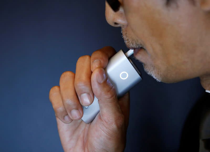 FILE PHOTO: A staff of British American Tobacco Japan demonstrates its new tobacco heating system device 'glo' after a news conference in Tokyo