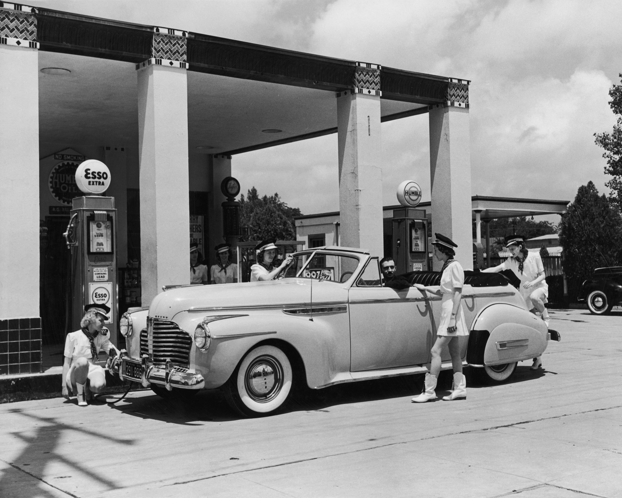 A group of uniformed female attendants cleaning a car for a customer at an Esso station, circa 1955.