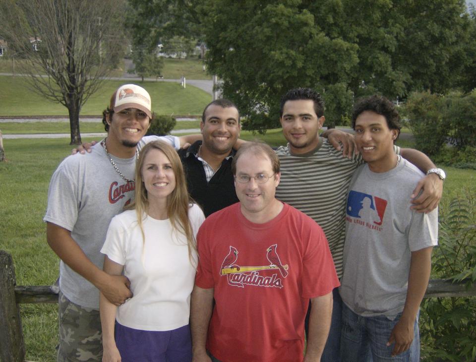 In this photo provided by TeriAnn Reynolds, TeriAnn and John Reynolds, front, pose with, from left, minor league baseball players Reynier González, Andres Rosales, Carlos Elias González and Jorge Rondón outside the Reynolds residence in Johnson City, Tenn., in July 2008. (Photo courtesy TeriAnn Reynolds via AP)