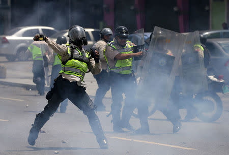 A riot police officer throws a rock as demonstrators rally against Venezuela's President Nicolas Maduro's government in Caracas, Venezuela April 10, 2017. REUTERS/Carlos Garcia Rawlins