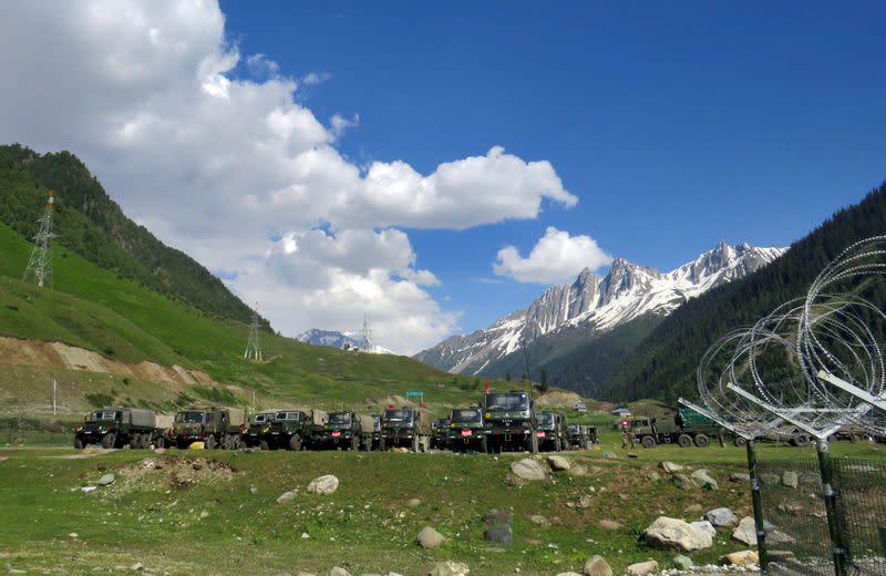 Indian army soldiers walk past their parked trucks at a makeshift transit camp before heading to Ladakh, near Baltal