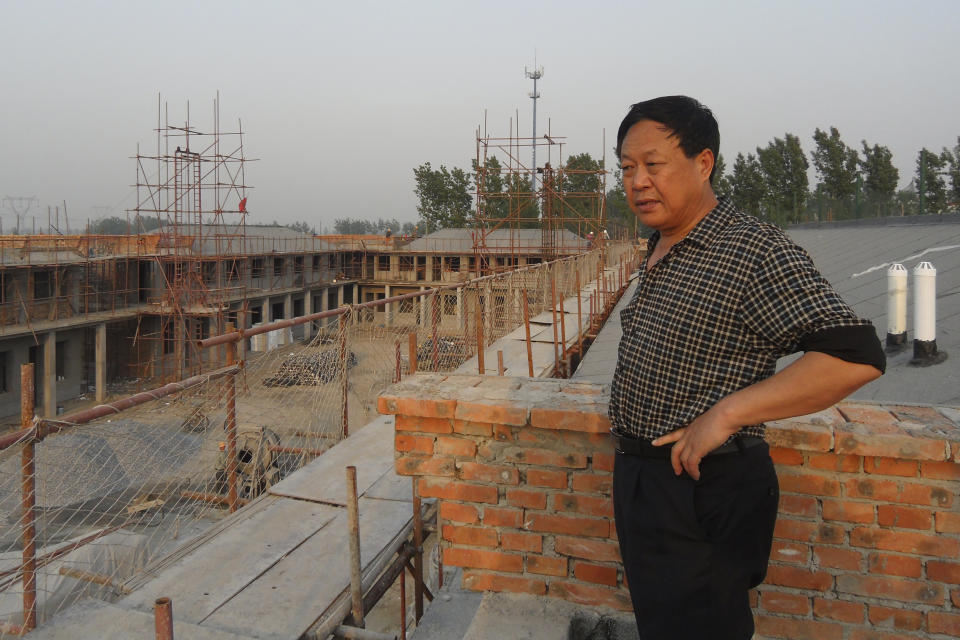 In this May 5, 2012, photo provided by the Legal Team of Dawu Group, Sun Dawu stands at a construction site for Dawu Town in Baoding in northern China's Hebei Province. A prominent Chinese pig farmer who was detained after praising lawyers during a crackdown on legal activists by President Xi Jinping's government has been sentenced to 18 years in prison on charges of organizing an attack on officials and other offenses. (Legal Team of Dawu Group via AP)