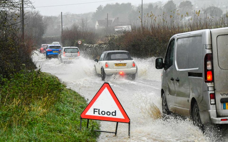 Vehicles drive through deep floodwater on the B3157 coast road at Bridport in Dorset