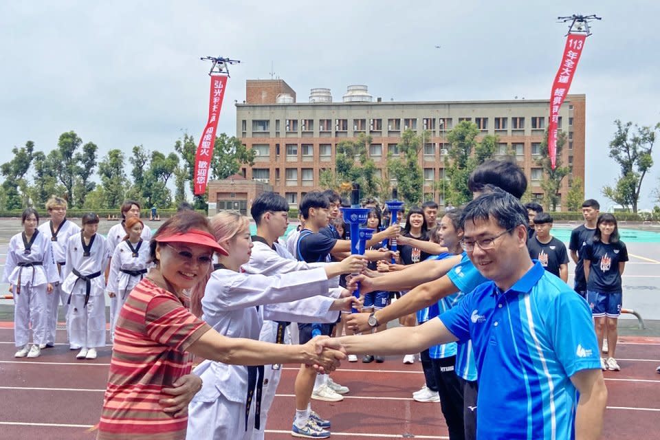 臺灣體大主任秘書陳添丁（右）及火炬手將聖火傳遞給弘光科大校長黃月桂（左）及火炬手。