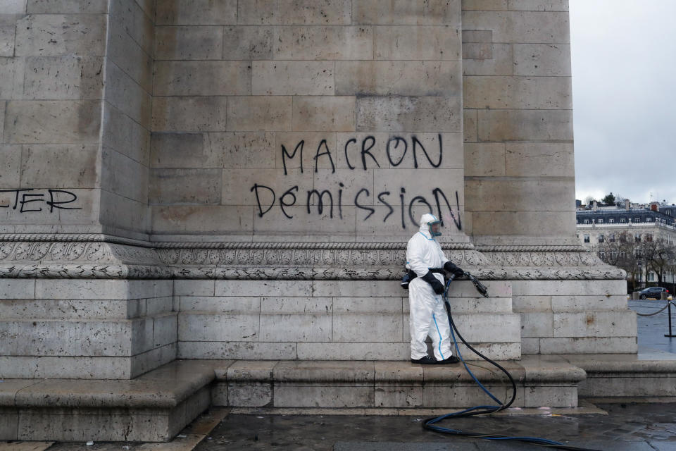 Un trabajador limpia una pintada en la que se lee 'Macron dimisión' (AP Photo/Thibault Camus)