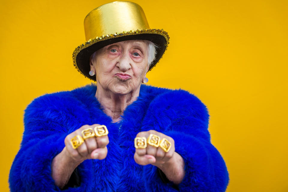 Old woman wearing gold hat and gold rings posing and looking rich.