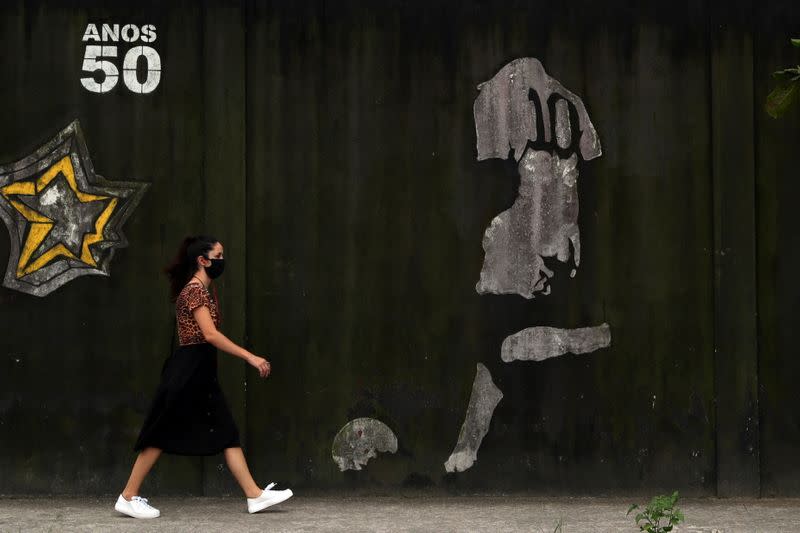 A woman walks by a mural depicting Brazilian soccer legend Pele in Santos