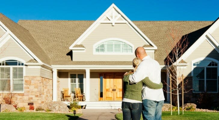 Image shows a couple standing arm in arm with their backs facing the camera as they admire their new home. SmartAsset analyzed IRS migration data to find the states to which rich Generation Xers are moving.
