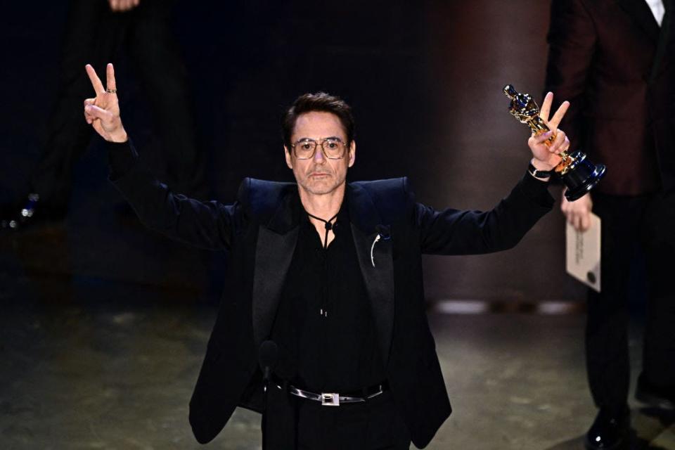 Robert Downey Jr. making peace signs while holding his Oscar.