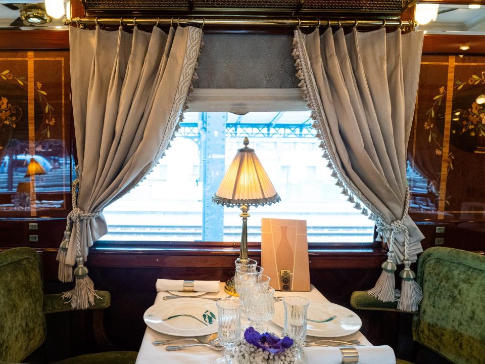 A dining table with a lamp on it on a luxury train