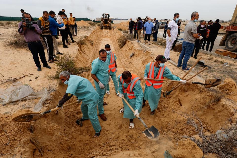 Men dig a mass grave to bury the bodies of Palestinians killed in Israeli strikes and fire, after they were transported from Al Shifa hospital in Gaza City for burial, in Khan Younis in the southern Gaza Strip November 22, 2023.  