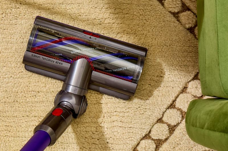 overhead shot of a cream colored rug being vacuumed.