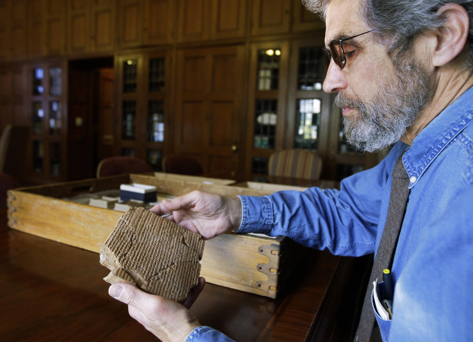 FILE - In this Oct. 16, 2008 file photo, Matt Stolper, director of the Persepolis Fortification Archive at the University of Chicago's Oriental Institute, examines a tablet that is part of a collection that provide a top-to-bottom look at life in the Persian empire 2,500 years ago. On Friday, March 28, 2014, a federal judge in Chicago ruled that survivors of a 1997 terrorist attack blamed partly on Iran can't seize museum pieces in U.S. collections to help pay a $412 million judgment against Iran. The ruling stems from a long-running legal battle that museum officials elsewhere watching closely. They feared their own collections could be put at risk if the judge had allowed collections of Persian antiquities at Chicago's Field Museum and the University of Chicago to be seized. (AP Photo/M. Spencer Green, File)