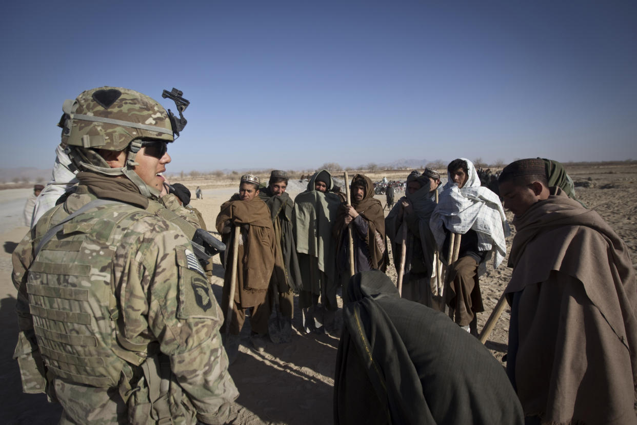 Afghan villagers, hired by the US Army to construct the canals for irrigation of their fields, wait for checking in to start their work outside the US Stout camp in Arghandab Valley of Kandahar province on January 4, 2011. (Behrouz Mehri/AFP via Getty Images)