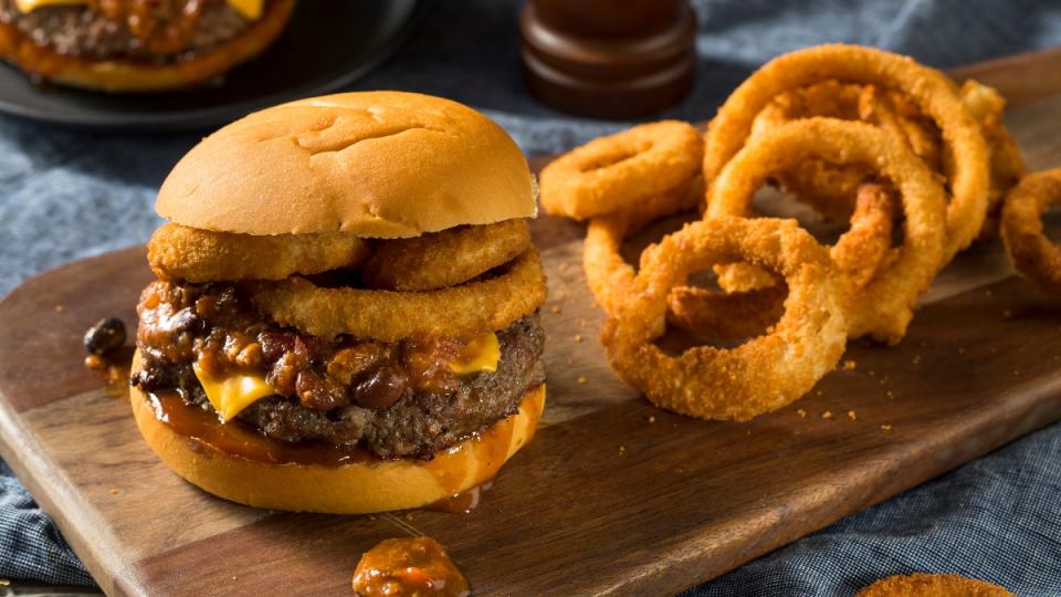 A burger topped with onion rings