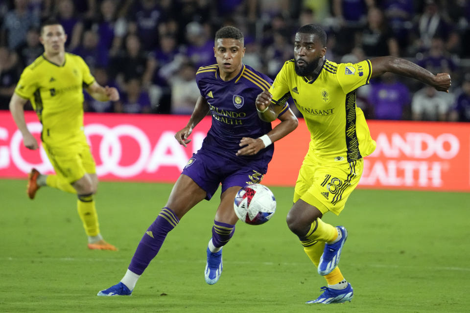 Orlando City defender Rafael Santos, center, and Nashville SC defender Shaq Moore (18) try to get position on the ball during the second half of an MLS playoff soccer match, Monday, Oct. 30, 2023, in Orlando, Fla. (AP Photo/John Raoux)