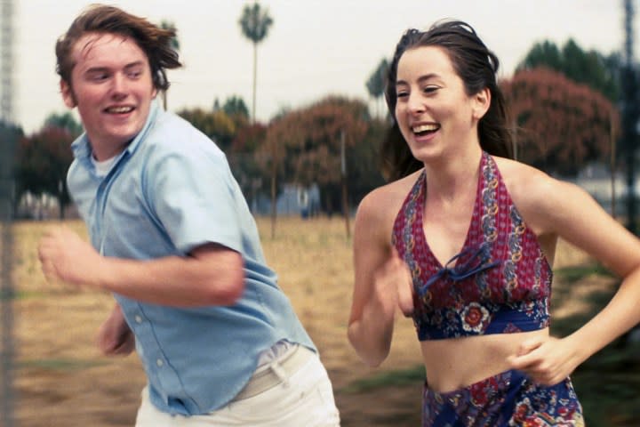 Cooper Hoffman and Alana Haim run together in Licorice Pizza.