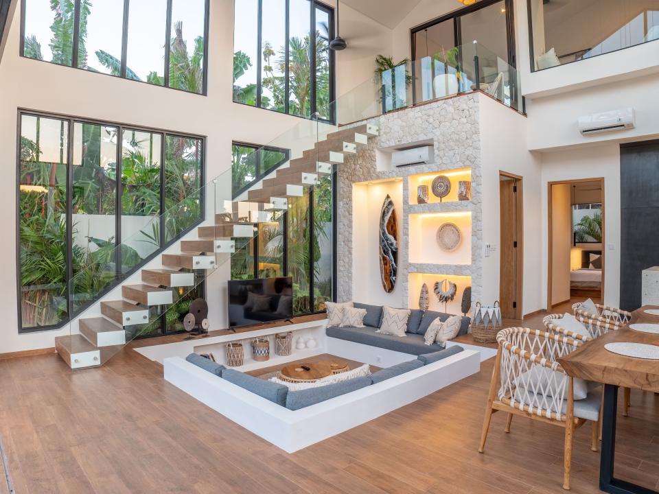 A modern living space with a conversation pit and a floating staircase.