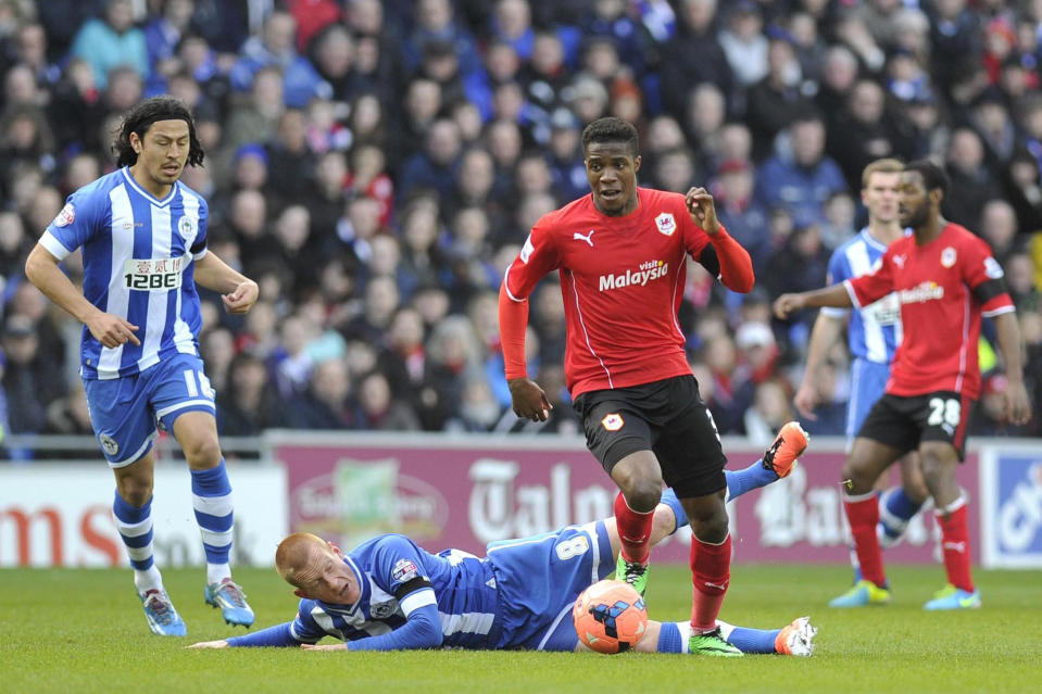 Cardiff City's Wilfried Zaha, centre, runs for the ball as Wigan Athletic's Ben Watson falls to the pitch during their FA Cup, Fifth round soccer match at The Cardiff City Stadium, Cardiff, Wales, Saturday Feb. 15, 2014. (AP Photo / PA ) UNITED KINGDOM OUT - NO SALES - NO ARCHIVES