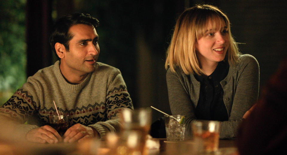 Kumail Nanjiani and Emily V. Gordon sit at a table, smiling and engaged in conversation, drinks in front of them