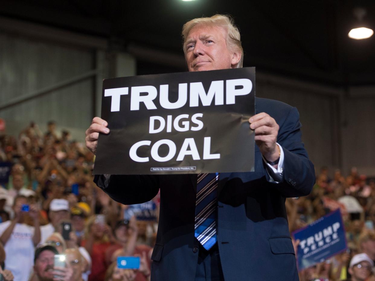 Donald Trump holds up a 'Trump Digs Coal’ sign as he arrives at a rally in West Virginia in August 2017 (AFP/Getty)